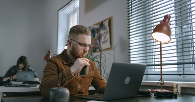 Man working on a laptop in an office while reviewing digital advertising content.
