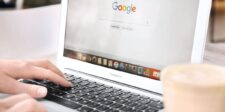 Close-up of a person using a laptop with the Google Search homepage open.