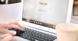 Close-up of a person using a laptop with the Google Search homepage open.