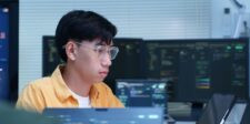 Cybersecurity researcher working at multiple computer screens displaying code.