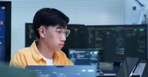 Cybersecurity researcher working at multiple computer screens displaying code.