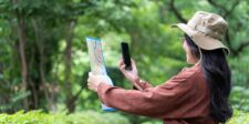 Google fined €403 million over location data processing in EU privacy case Woman comparing a paper map with a smartphone while navigating outdoors.