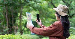 Woman comparing a paper map with a smartphone while navigating outdoors.
