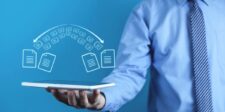 Kiteworks says systems can restart after rare shutdown advisory Business professional holding a tablet beneath digital icons representing secure file transfers.