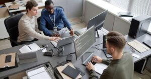 Cybersecurity team reviewing code and system activity across multiple computer screens.