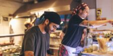 Restaurant workers preparing food behind the counter in a busy kitchen.