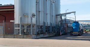 Tanker truck loading pulverized chalk beside industrial silos in Grötö, Sweden.
