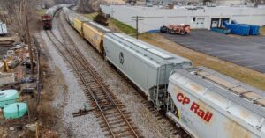 Grain hopper railcars traveling on freight tracks, including a CP Rail car.