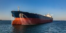 Large oil tanker anchored on calm water under a clear blue sky.