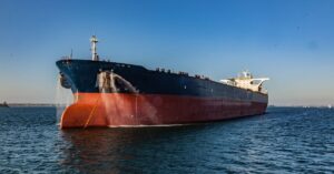 Large oil tanker anchored on calm water under a clear blue sky.