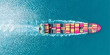 Aerial view of a container ship carrying colorful freight containers across the ocean.