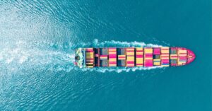 Aerial view of a container ship carrying colorful freight containers across the ocean.