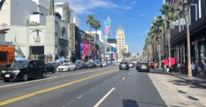 Hollywood Boulevard in Los Angeles with theaters, palm trees, traffic, and pedestrians.