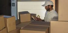 UPS and FedEx holiday surcharges begin with bulky U.S. parcels Delivery worker checking packages beside a van loaded with cardboard parcels.