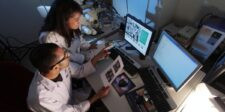 Two scientists reviewing microscopy images and research data in a laboratory.