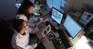 Two scientists reviewing microscopy images and research data in a laboratory.