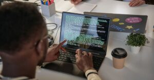 Developer reviewing code on a laptop, illustrating research showing AI coding agents increase code output while adding pressure to code review.