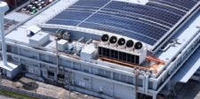 Large data center facility with rooftop solar panels and cooling infrastructure, illustrating the physical costs behind AI expansion.