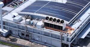 Large data center facility with rooftop solar panels and cooling infrastructure, illustrating the physical costs behind AI expansion.