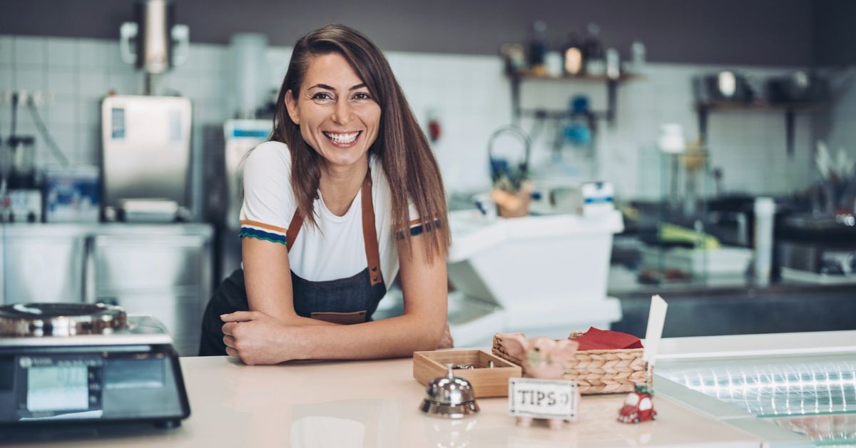 Woman smiling behind a cafe counter.