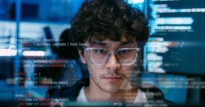 Software developer working with code displayed across multiple computer screens.