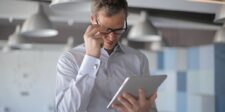 Business professional reviewing an email on a tablet with a concerned expression.