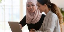 Two colleagues reviewing work together on a laptop