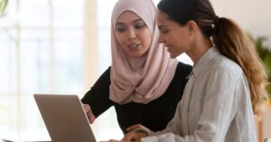 Two colleagues reviewing work together on a laptop