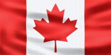 Close-up of a red and white Canadian flag with a maple leaf on rippling fabric.