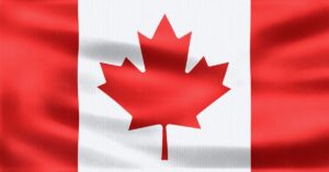 Close-up of a red and white Canadian flag with a maple leaf on rippling fabric.