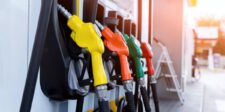 Yellow, orange, green and red fuel nozzles lined up at a gas station.