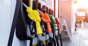 Yellow, orange, green and red fuel nozzles lined up at a gas station.