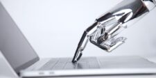 Robotic hand pressing a key on a laptop keyboard