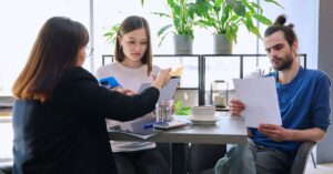 Business owners reviewing commercial loan documents with a financial advisor during a refinancing discussion.