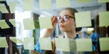Entrepreneur planning business growth with sticky notes on a glass wall.