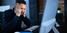 EY breach exposes tax data held for major financial clients Stressed professional looking at a computer, illustrating the EY data breach involving client tax and financial information.