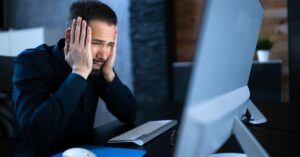 Stressed professional looking at a computer, illustrating the EY data breach involving client tax and financial information.