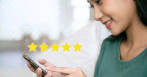 Woman using a smartphone beside a five-star rating graphic, illustrating online reviews and business reputation.