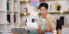 Best font size for business cards: a practical print guide Graphic designer reviewing printed design proofs at a desk, illustrating business card typography and print sizing.