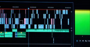 Video-editing timeline with multiple coloured video and audio tracks on a monitor.