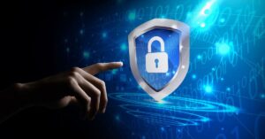 Hand pointing toward a digital shield with a padlock against a blue binary-code background.