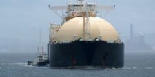 LNG freight rates slide as new carriers crowd the Atlantic LNG carrier sailing near an industrial port, illustrating pressure on liquefied natural gas freight rates.