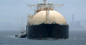 LNG carrier sailing near an industrial port, illustrating pressure on liquefied natural gas freight rates.