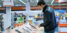Customer examining smartphones in an electronics store, illustrating low-cost Android phones found with preinstalled firmware malware.