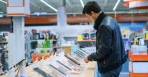 Customer examining smartphones in an electronics store, illustrating low-cost Android phones found with preinstalled firmware malware.