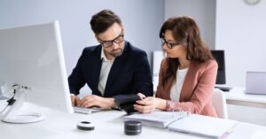 Business professionals reviewing financial records and documents at a computer while preparing to form an LLC.