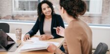 Marketing contract checklist: what to include before you sign Business owner and marketing professional reviewing contract documents during a client meeting.