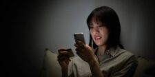 Woman browsing on her smartphone while holding a payment card, illustrating Meta's upcoming product-browsing changes to Facebook and Instagram ads.