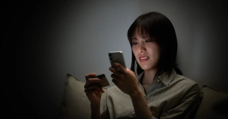 Woman browsing on her smartphone while holding a payment card, illustrating Meta's upcoming product-browsing changes to Facebook and Instagram ads.