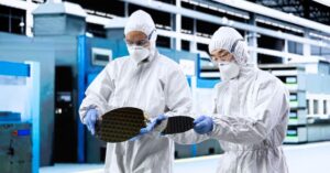 Semiconductor workers inspecting silicon wafers in a cleanroom, illustrating labour pressure at Micron’s Taiwan memory operations.